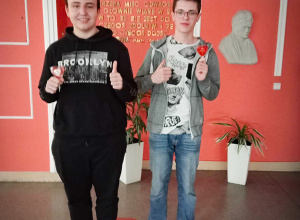 dwóch uczniów stoi na tle ściany z podobizną patronki szkoły.